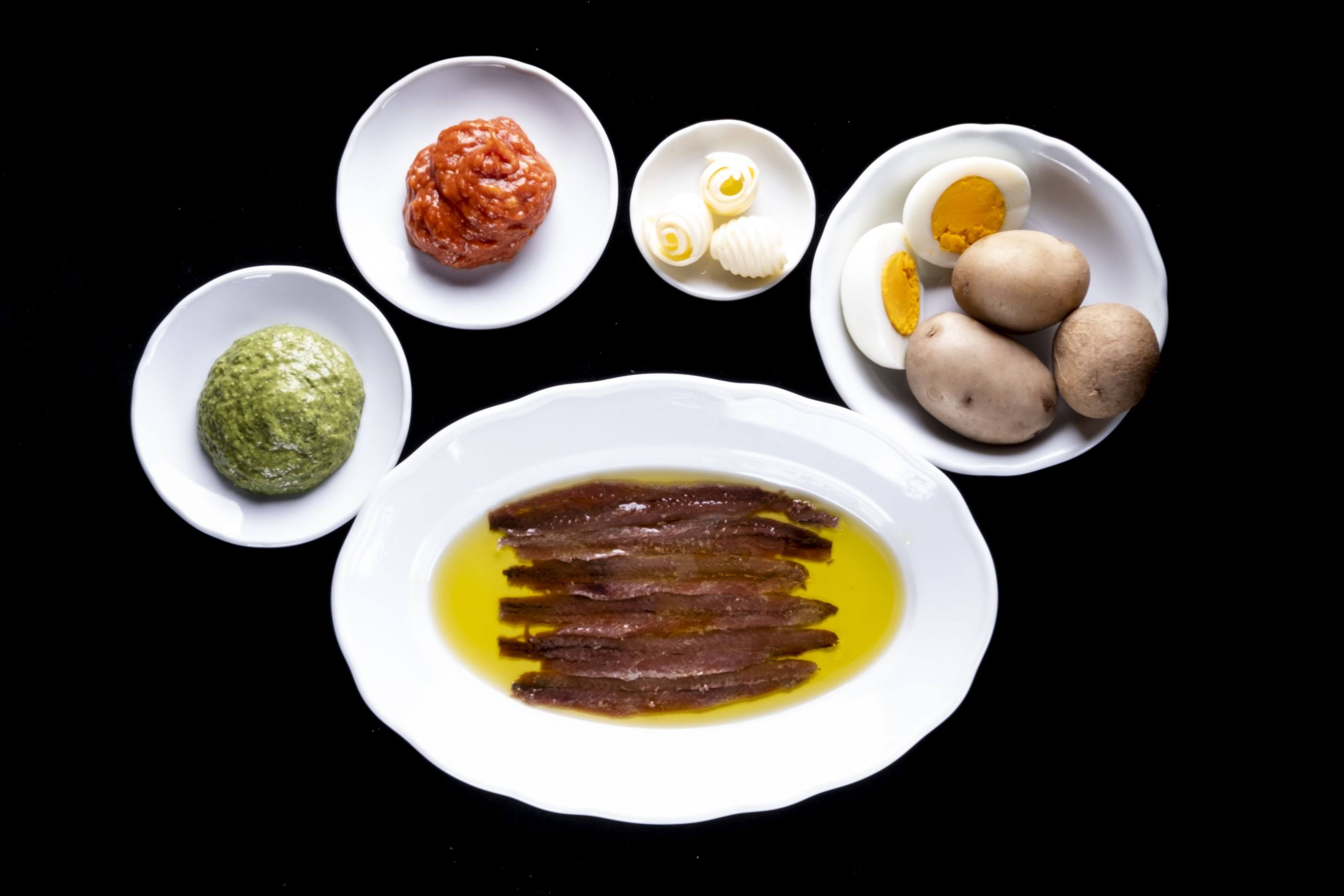 Acciughe in olio con bagnetto verde, bagnetto rosso, riccioli di burro, uova sode e patate novelle