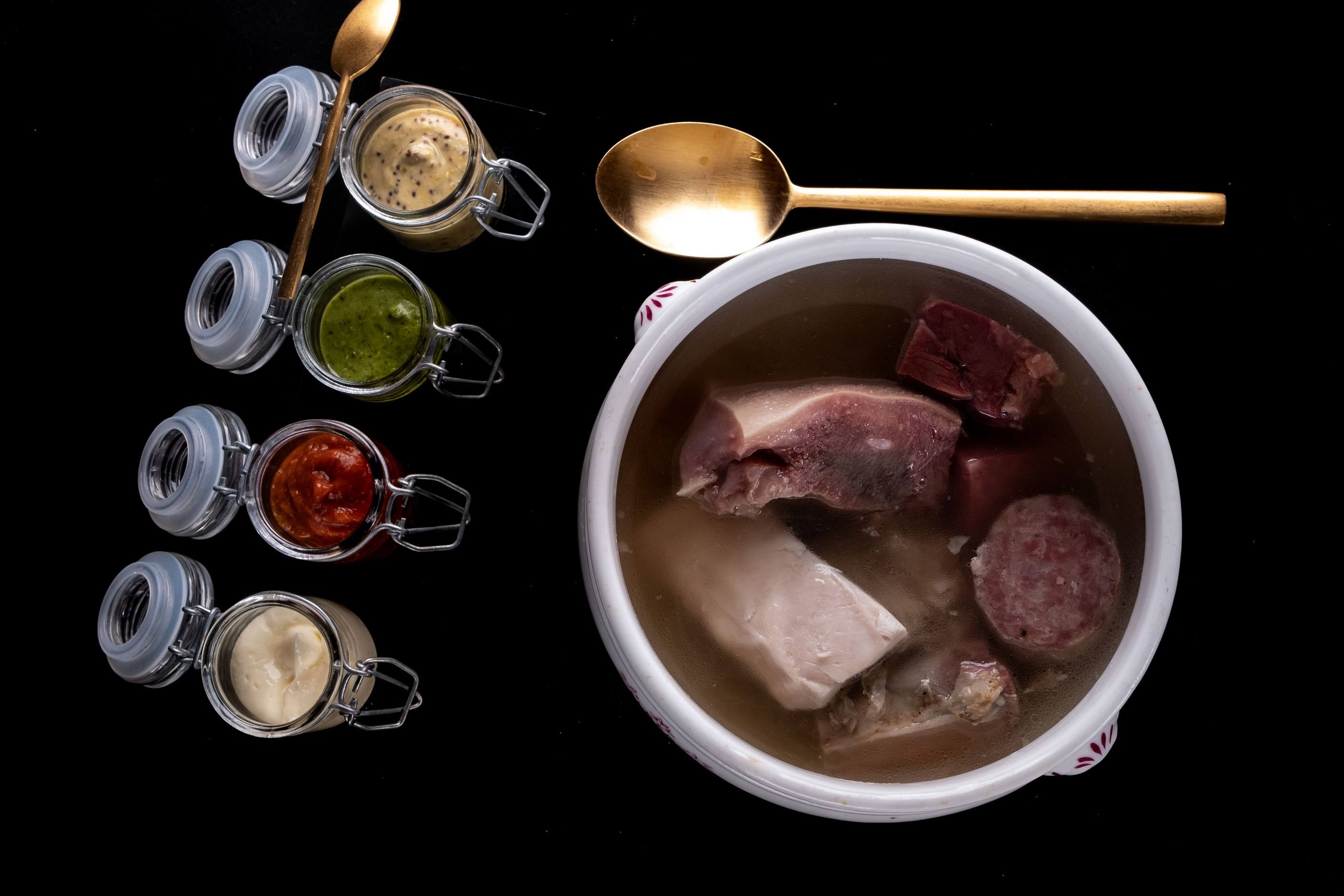 Bollito misto in una zuppiera con quattro vasetti di salse: maionese, bagnetto verde, bagnetto rosso e senape