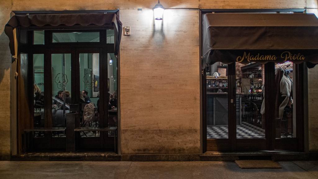 La facciata di Madama Piola in via Ormea di sera, con le vetrine illuminate e le tende